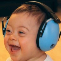 Smilende gutt med lyseblå høretelfoner Liten gutt som smiler stort. Han har på seg lyseblå høretelefoner